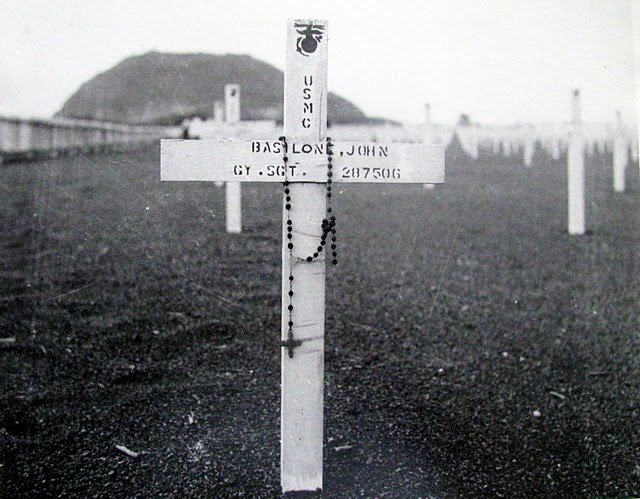 A rosary hangs from the wooden cross making the grave of Marine Gunnery Sgt. John Basilone at Iwo Jima. He had received the Medal of Honor at Guadalcanal and was one of the 6,821 Americans killed on the 8-square-mil island. Another 12,400 Americans were wounded in the 36-day battle. Some 20,000 Japanese defenders lost their lives. Photo provided by Dick Honyak