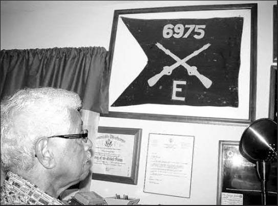 Richard Smith of Port Charlotte looks at a guide-on in a place of honor on his office wall. He was presented the battalion guide-on by his regimental commander for being the unit's outstanding soldier. Sun photo by Don Moore