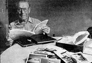 George Lentz looks through a booklet prepared by the 385th Bomb Group, which he flew with in World War II. The pile of pictures in the foreground is of him and his service buddies over 60 years ago. Sun photo by Don Moore