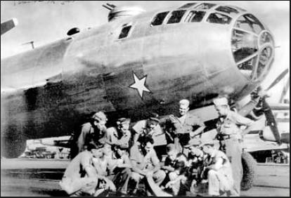 The crew of "Skookum," a B-29 bomber in the background, checks a map just before taking off for Aomori, Japan. Capt. Harold Keathley is squatting down at the right front with a straw hat on. Photo provided