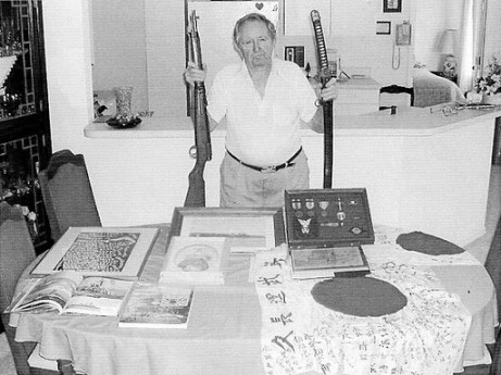 Harry Allcroft of Port Charlotte holds a Japanese caarbine and a samurai sword he "liberated" from some of the contraband found aboard the Tachibana Maru. Sun photo by Don Moore
