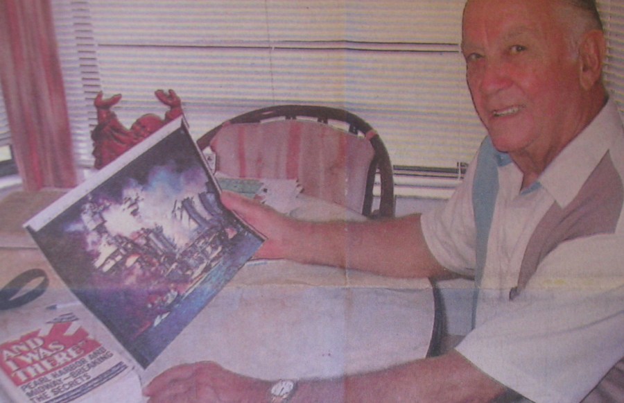 Dale Augerson of Rotonda, Fla. looks at a picture of the USS West Virginia going up in flames at dockside during the Japanese attack on Pearl Harbor, Dec. 7, 1941. He served as a baker aboard the battleship during the attack 54 years ago today.