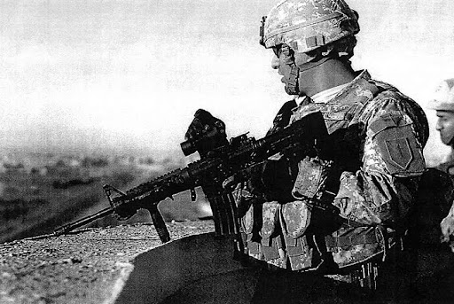 A soldier with the 1st Infantry Division watches for insurgents from the top of an eight-story hotel in Mosul with his M-4 rifle ready for use. With him is an Iraqi colonel learning how American forces fight. Army Photo by Spec. Bryanna Poulin