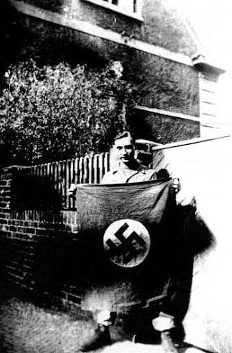 Gantzer holds a Nazi flag outside the apartment his anti-tank unit was livin in in Berlin. Photo provided by Floyd Gantzer