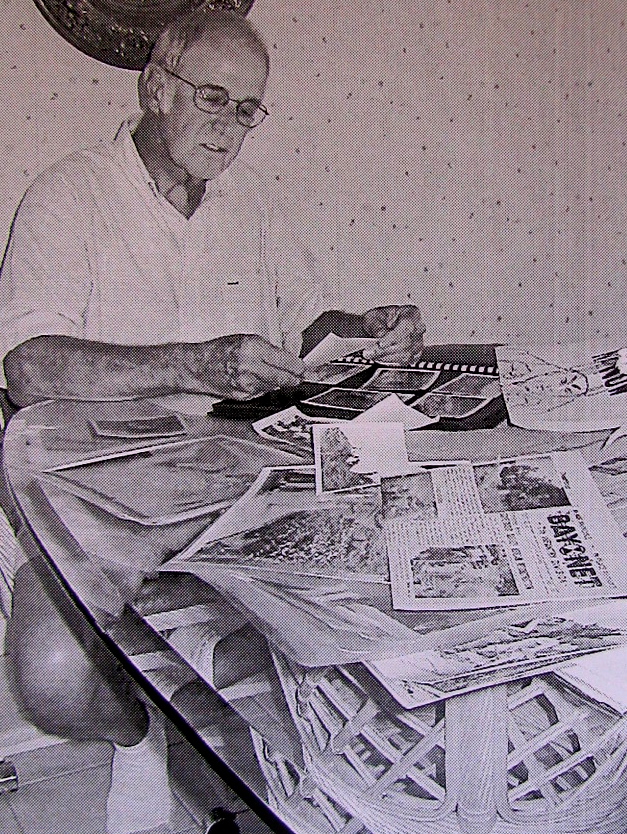 Roger Burton looks through a table full of pictures, papers and clippings covering his time as editor of a weekly newspaper at the end of the Korean War. He and his wife, Nancy, now live in Punta Gorda . Sun photo by Don Moore