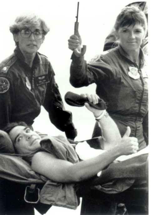 Black Hawk pilot Mike Durant gives thumbs up to the photographer while being sheltered from the rain by two nurses who accompanied him on the C-141 to Ramstein Air Force base in Germany, Photo courtesy Mike Durant/MikeDurant.com
