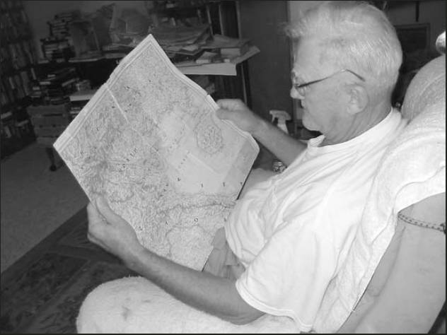 John Schoell looks at a map of Korea trying to find the two towns where his regiment landed during the war. Sun photo by Don Moore