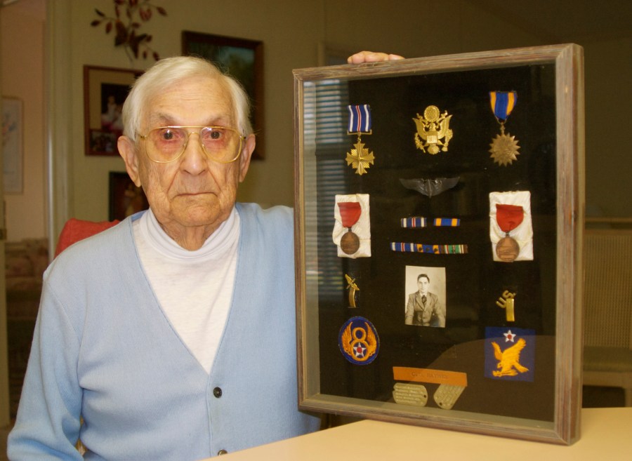 Raynes holds a shadow box full of his World War II military medals, bars and patches that hangs on his office wall in La Casa. At the top left in the box is the Distinguished Flying Cross, just below the Medal of Honor for surviving 25 combat missions over Nazi-occupied Europe a lifetime ago. Sun photo by Mary Auenson