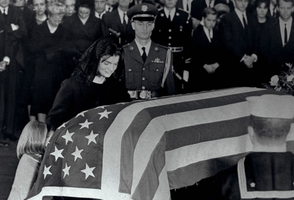 First Lady Jacqueline Kennedy kneels beside the coffin of her slain husband in the Rotonda of the capitol.