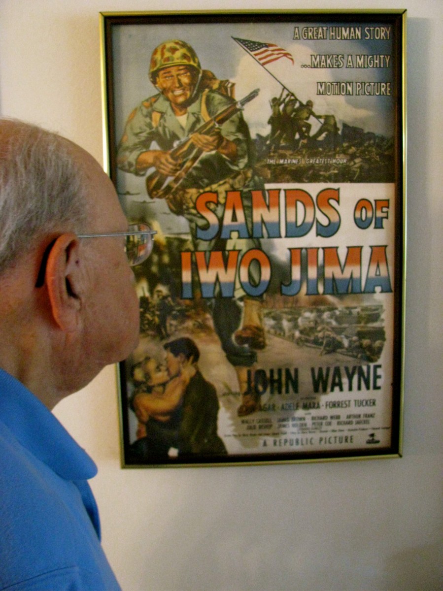 Leon Gumley of Sarasota looks at a movie poster on his living ­room wall advertising "Sands of Iwo Jima" in which he played in with John Wayne after being a glider pilot in World War II. Sun photo by Don Moore