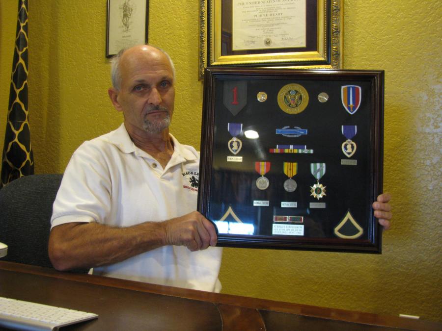 Ron Heurlin today at 66 at his home in Punta Gorda Isles. He's holding a shadow box that contains: Two Purple Heart medals, Combat Infantryman's Badge, National Defense Service Medal and Vietnamese Campaign Medal he received for serving in the Vietnam War. Sun photo by Don Moore