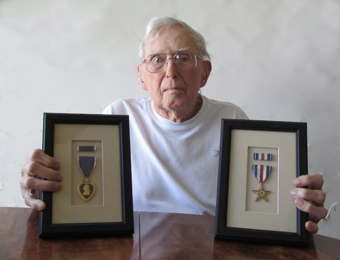  Former Electrician's Mate !/C Richard Johnson of Circlewood subdivision in Venice holds his "Purple Heart" and "Silver Star" medal for gallantry. He served aboard the carrier USS Ticonderoga during WW II when it was hit by two Kamikazes. His actions during the fire help save the carrier. Sun photo by Don Moore