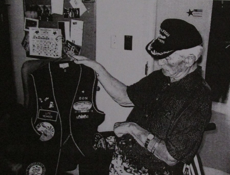 Don Alger looks at the military vest he wears to submarine gatherings with his old Navy buddies. He laments the passing of time and the passing of many of his World War II service friends. Sun photo by Don Moore