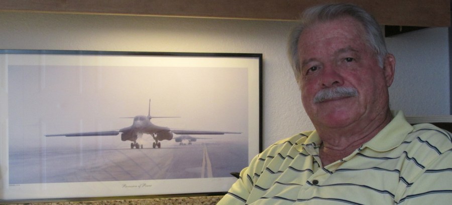 Chet Buckenmaier of Burnt Store Marina sits beside a picture of a B-1 Bomber he helped design and build while serving in the Air Force for almost 20 years. Sun photo by Don Moore