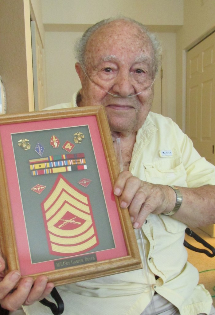  Buffa today at 94 holding a shadowbox of his sergeant stripes and medals he received while serving in World War II. Sun photo by Don Moore