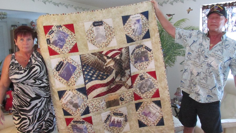 Sharon Hirkey and her husband, Donald, hold a quilt she made to be presented at a party in Rayne, La. on Veterans' Day. Each year Hirkey and a dozen of his Vietnam buddies get together twice. On Veterans' Day they meet at 'Joe's Place' in Rayne, La. and some other spot around the country. The quilt, with a picture of each of his 12 members of his fire team when they served in 'Nam, will be on display at Joe's Place watering hole for the world to see. Sun photo by Don Moore