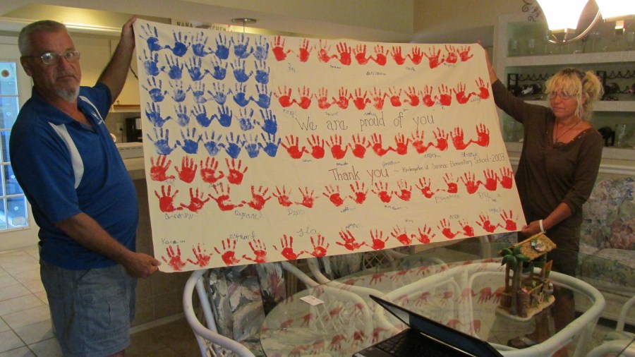 Former sergeant Klein and his wife, Sharon, hold a banner a group of grade-school kids made for him at a school in Plattsburgh, N.Y., where he was stationed at a SAC base for years. The flag went with him to Iraq in 2006 and 2007. Sun photo by Don Moore 