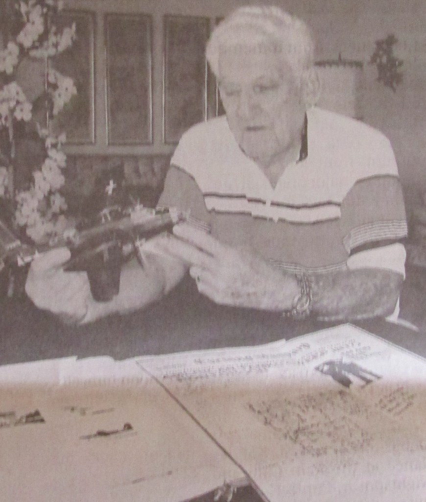 Dvorak holds a model of an A-20 Havoc attack bomer like the one in which he flew during WW II. In front of him is a copy of the London Evening Standard for Aug. 2, 1944 in which he is pictured on the front page. Sun photo by Don Moore