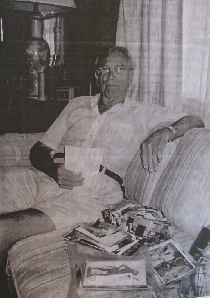 Wright is pictured looking at a stack of old photographs about his life decades ago. Sun photo by Don Moore