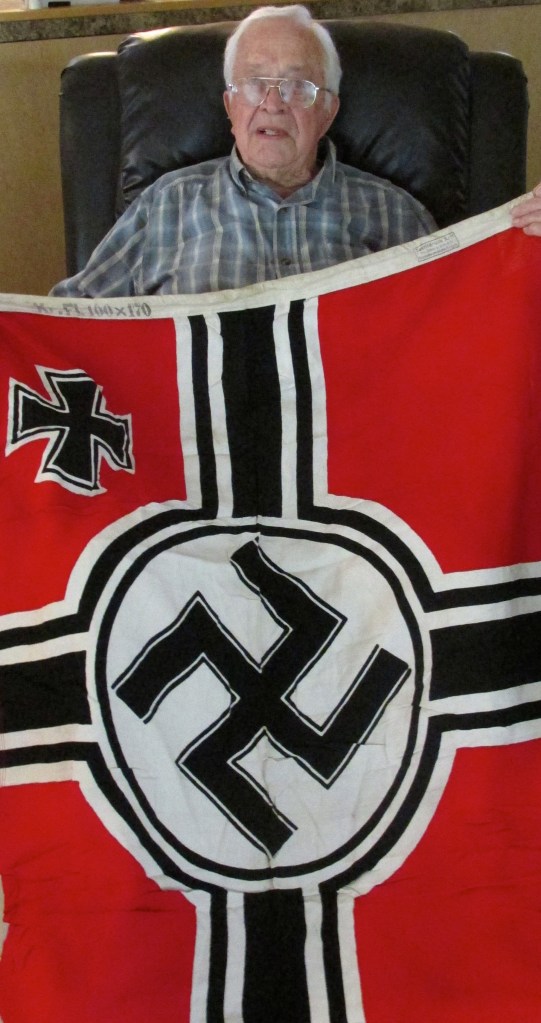  Lubold holds a Nazi flag he got from a German workman while serving at the U.S. Navy facility in Bremerhaven in 1947. Sun photo by Don Moore